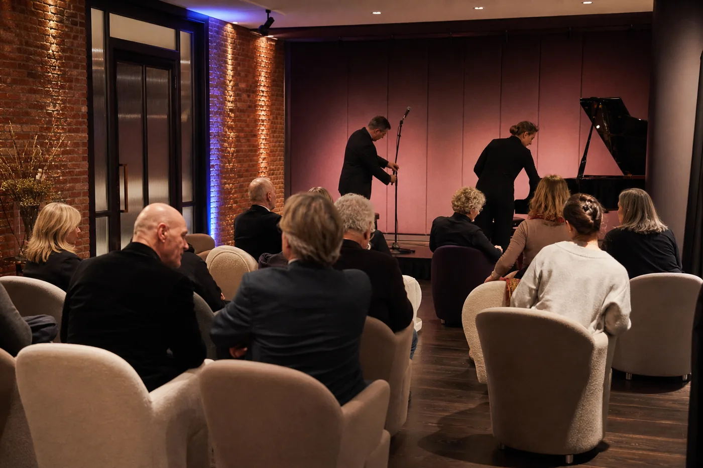 Intieme programmasalon met verplaatsbare stoelen en zacht podiumlicht